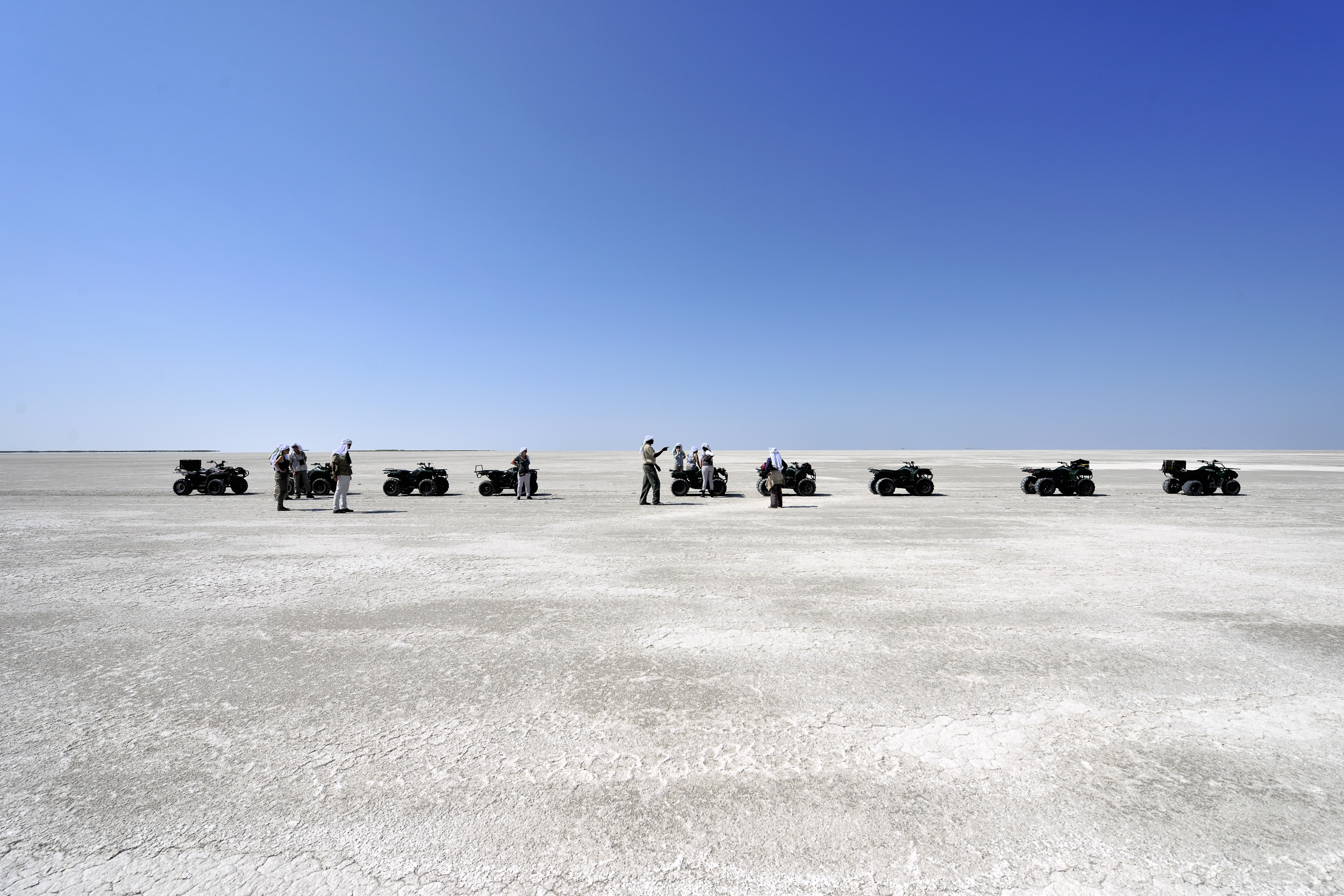 A group of travelers exploring the vast, otherworldly salt flats on quad bikes.