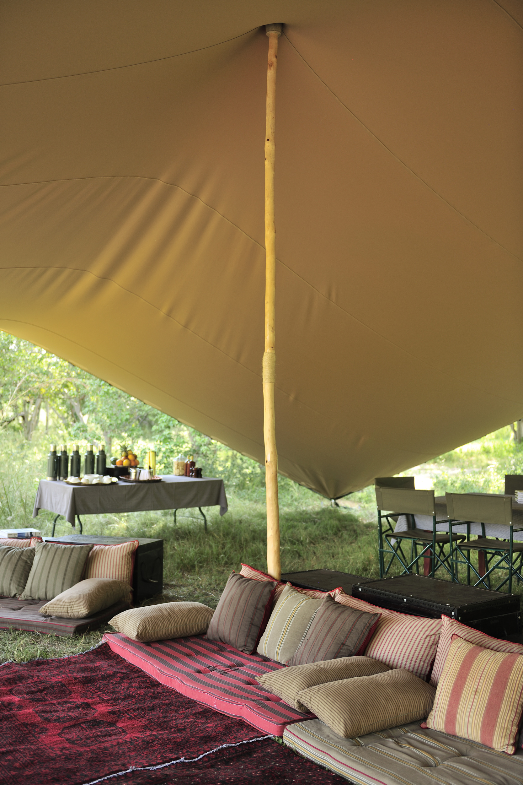 A shaded lounge area featuring colorful cushions and a buffet table, blending comfort and style on a mobile safari.