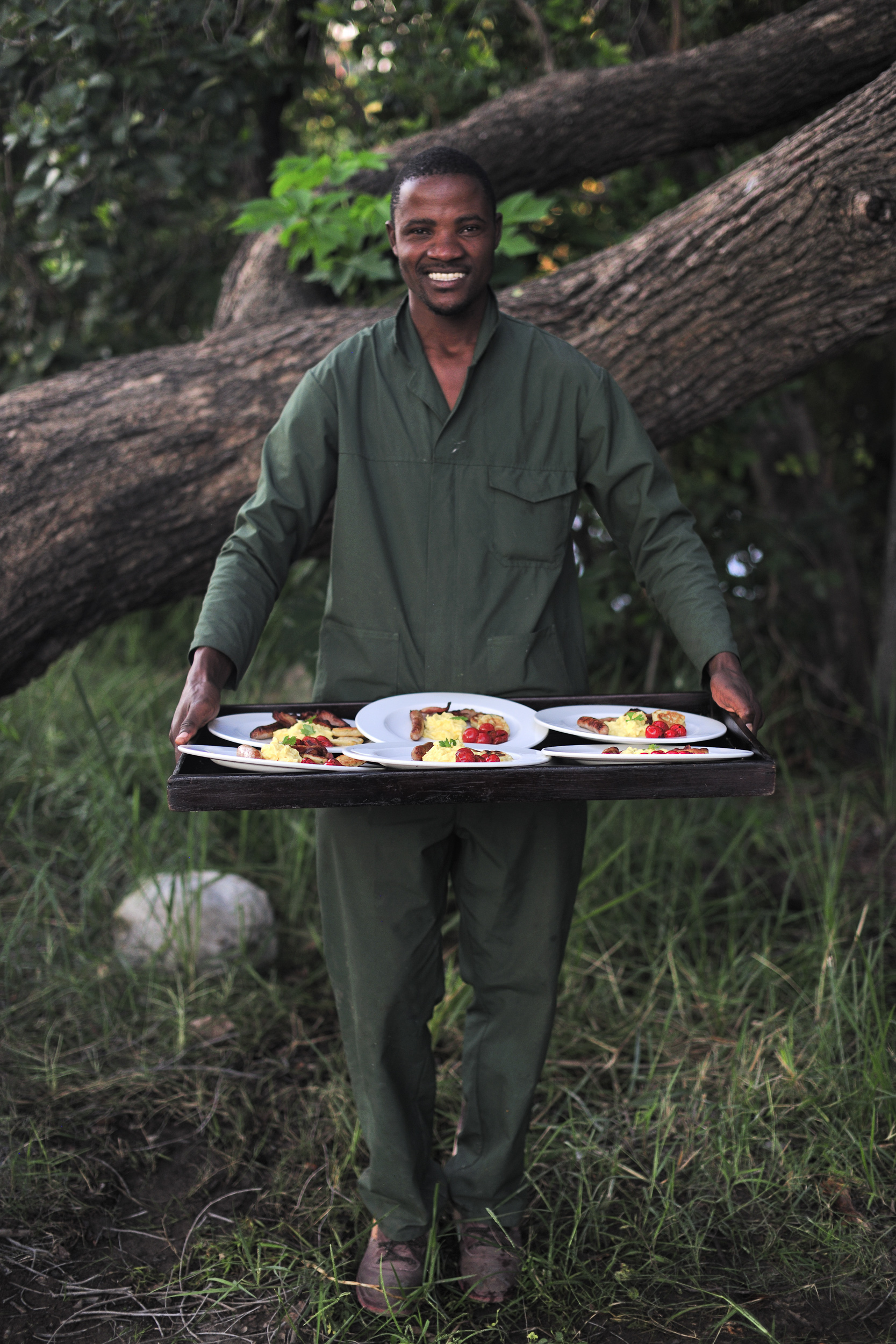 A smiling staff member serving a delectable safari breakfast amidst nature.
