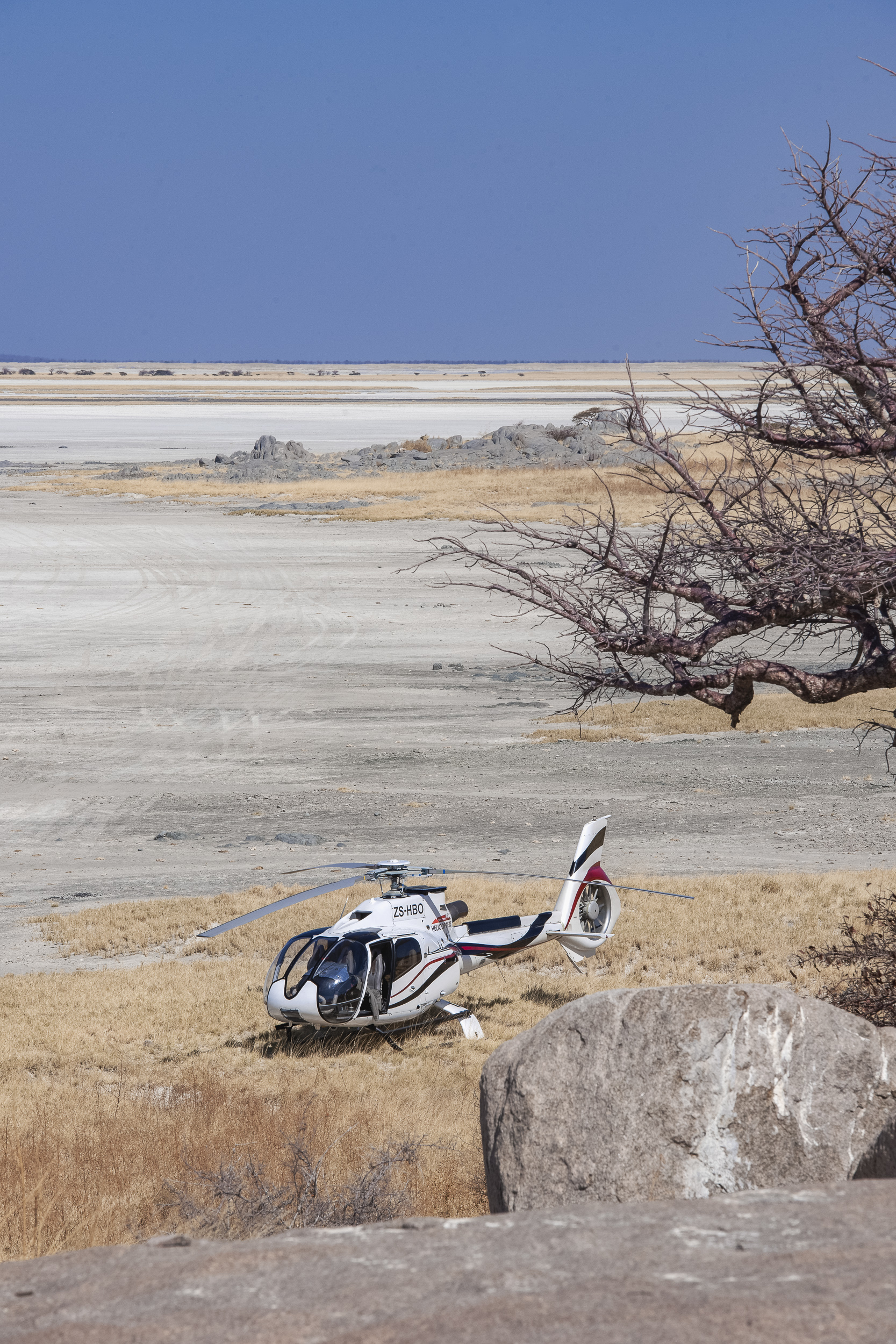 A helicopter rests amid Botswana’s dramatic salt pans, ready for the next unforgettable adventure.